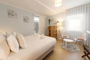 a bedroom with a white bed with white pillows at Fika Guest House in Nazaré