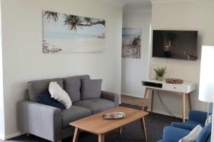 uma sala de estar com um sofá e uma mesa em Sunset On Esplanade em Perth