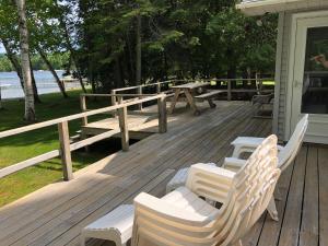 a deck with benches and picnic tables on a house at New! Birch Cove Bungalow - Gorgeous Lakefront! in Honor