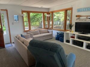 ein Wohnzimmer mit einem Sofa und einem TV in der Unterkunft New! Birch Cove Bungalow - Gorgeous Lakefront! in Honor