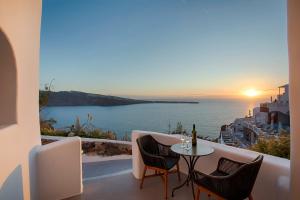 a table and chairs on a balcony with a view of the ocean at ArmonOia Luxury Caves in Oia