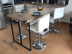 einen Holztisch in einer Küche mit zwei weißen Stühlen in der Unterkunft Stunning sea views from luxury 4 bed apartment close to beach at Cap Ras in Llança