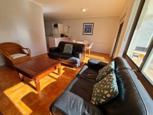 sala de estar con sofá de cuero negro y mesa en West Beach Lagoon 204 - Ground Floor! en Perth