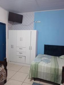 1 dormitorio con 1 cama, armarios blancos y una pared azul en Kitnet Pousada da T, en Pelotas