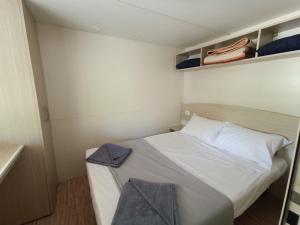 Un pequeño dormitorio con una cama blanca y estanterías en Camping Karavomilos en Sami