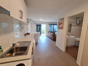 a white kitchen with a sink and a living room at West Beach Lagoon 206 - Sleeps Three! Value!!! in Perth