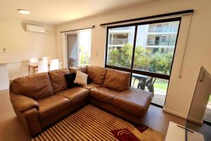 a brown leather couch in a living room with a large window at West Beach Lagoon 206 - Sleeps Three! Value!!! in Perth