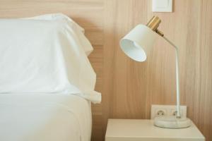 a white bed with a lamp on a night stand at Select Porto Suites in Porto