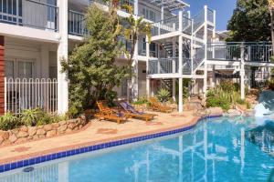 een zwembad met stoelen en een gebouw bij West Beach Lagoon 213 - Corner Unit! in Perth