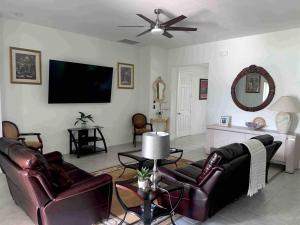 sala de estar con muebles de cuero y TV de pantalla plana en Home sweet home, en Port Saint Lucie