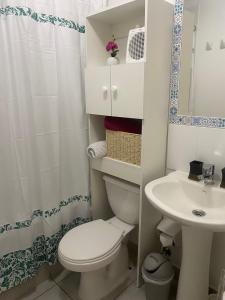 a white bathroom with a toilet and a sink at Bonito y acogedor departamento in Los Ángeles