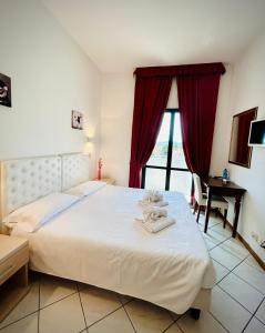 a bedroom with a large white bed with a window at Hotel Romagna in Cesena