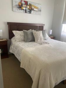 1 dormitorio con 1 cama con sábanas y almohadas blancas en Bonito y acogedor departamento en Los Ángeles