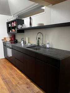 een keuken met een zwart aanrecht en een wastafel bij Penthouse at The Bären 180º View in Zweisimmen