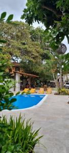 una piscina con sillas amarillas y árboles en Pousada Varanda do Sol, en Arraial d'Ajuda