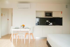 cocina blanca con mesa blanca y sillas en room Select Porto Suites, en Oporto