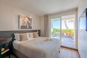 a bedroom with a bed and a large window at Hôtel La Plage in Sainte-Maxime
