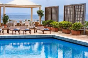 uma piscina com cadeiras e uma mesa e o oceano em Chios Chandris em Quios