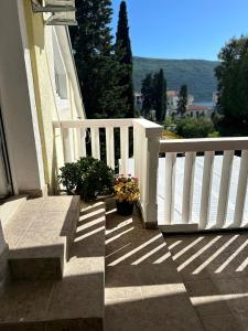 a porch with a white railing and potted plants at Apartman Sun house Kumbor 2 in Herceg-Novi +6 photos