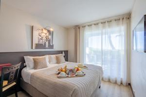 Un dormitorio con una cama con una bandeja de comida. en Hôtel La Plage, en Sainte-Maxime
