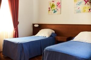 セビリアにあるアパルタメントス サン アンドレスの青と白のシーツが備わる客室のベッド2台