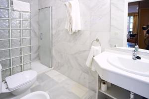 Baño blanco con lavabo y aseo en Apartamentos San Andres, en Sevilla