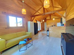salon z żółtą kanapą i kuchnią w obiekcie Le Chalet w mieście Malause
