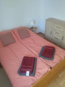 uma cama com lençóis cor-de-rosa e almofadas castanhas em Kuća za odmor Jezero em Ostrovo