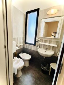 uma casa de banho com 2 WC, um lavatório e um espelho. em Hotel Romagna em Cesena