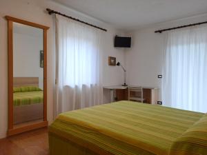 een slaapkamer met een groen bed en een spiegel bij Casa Erica in Falcade