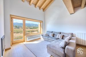 a living room with a couch and a large window at Espectacular apartamento dúplex Bellver in Bellver de Cerdanya 
