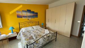 a bedroom with a bed and a yellow wall at Casa vacanze da Roberta a pochi km da Oristano in Simaxis