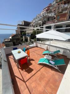 eine Terrasse mit einem Tisch, Stühlen und einem Sonnenschirm in der Unterkunft Casa Positano in Positano