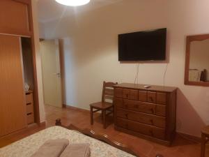 ein Schlafzimmer mit einer Kommode mit einem TV an der Wand in der Unterkunft Angela Beach Place in Vila Baleira