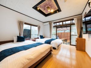 two beds in a room with windows and a chandelier at Yufuin Wasaku in Yufu