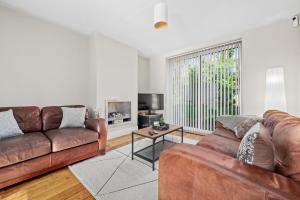 a living room with two leather couches and a tv at Fantastic, modern 3 bedroom house in Manchester