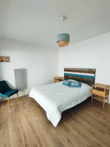 een slaapkamer met een bed en een blauwe stoel bij Le Panorama de la Corniche in Saint-Hilaire-de-Riez