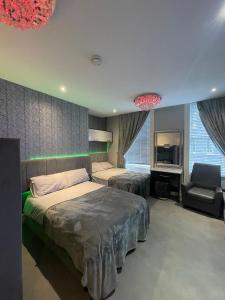 a bedroom with two beds and a chair and a television at 19 Rodney Street Apartments in Liverpool