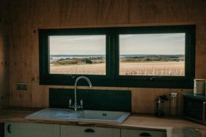 a kitchen with a sink and a window with a field at Dome Meadow 1 with Log Burning Tub At Tapnell Farm in Yarmouth +10 photos