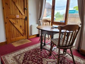 a wooden table and chair in a room with a door at Haywains Self-Catering at Boningale Manor in Wolverhampton