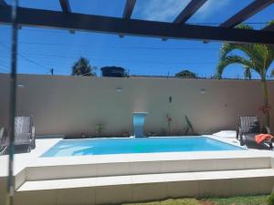 a swimming pool in front of a white wall at Recanto da Sulla - JAUÁ in Jauá