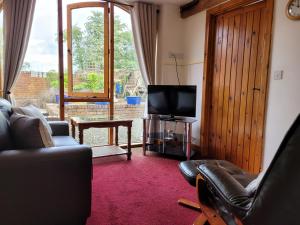 ein Wohnzimmer mit einem Sofa und einem TV in der Unterkunft Haywains Self-Catering at Boningale Manor in Wolverhampton