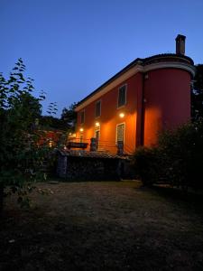 een groot rood huis met 's nachts verlichting bij Podere San Raffaele in Aiello del Sabato