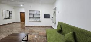 HOMESTAY - AC 3 BHK NEAR AlRPORT في تشيناي: غرفة معيشة مع أريكة خضراء وطاولة
