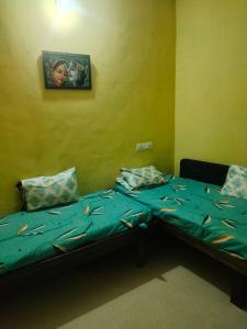 a bedroom with two beds and a picture on the wall at Dwarka Home Stay 2 Only family in Dwarka