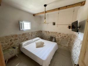 Schlafzimmer mit einem weißen Bett und einem TV in der Unterkunft Trullo Del Salento in San Vito dei Normanni