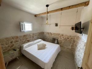 a bedroom with a white bed and a television at Trullo Del Salento in San Vito dei Normanni