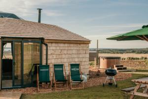 a group of chairs and a grill next to a building at Dome Meadow 1 with Log Burning Tub At Tapnell Farm in Yarmouth