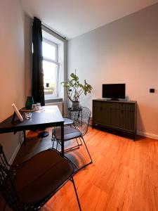 een woonkamer met een tafel en stoelen en een televisie bij Apartments am Hafen in Stralsund