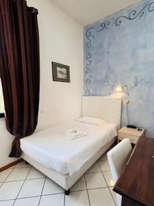 a small bedroom with a bed and a table and a desk at Hotel Romagna in Cesena